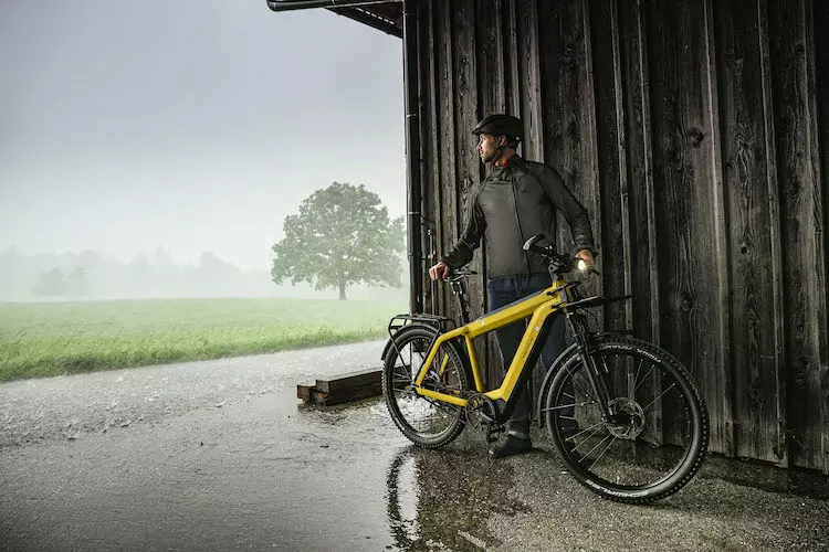 Homme à côté d'un vélo électrique Supercharger dans un paysage brumeux