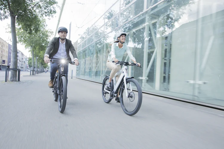 Femme et homme qui se promènent en ville avec des vélos électriques Stromer