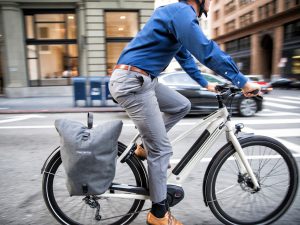A man with blue shirt and grey pant riding an ebike