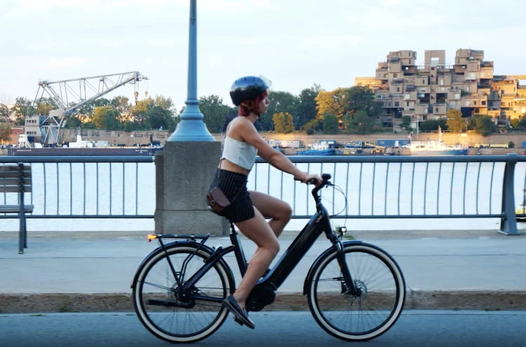 Une fille fait du vélo électrique pour femmes d'O2feel au bord de l'eau